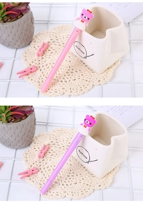 Pink and purple cartoon unicorn pens with cute bear toppers on a creative desktop setup