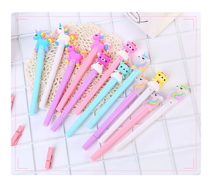 Flat lay of colorful macaron pens with cute cartoon unicorn and bear toppers on mesh