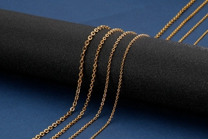 Macro shot of gold stainless steel cable chains in multiple sizes on black display