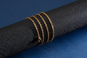 Detail of a golden stainless steel O-chain necklace with a lobster clasp on a dark base