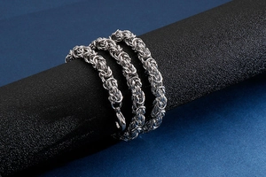Close-up of stainless steel keel chain necklace with lobster clasp on a black pillar