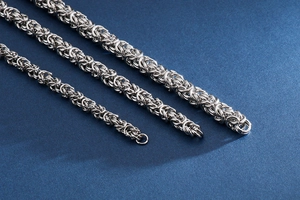 Three Byzantine stainless steel bone chains in varying widths on blue background