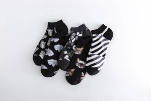 Detail of five pairs of cotton blend crew socks featuring cat and geometric patterns
