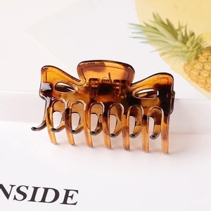 Close-up of a large amber tortoiseshell hair claw clip with a glossy finish on white backdrop