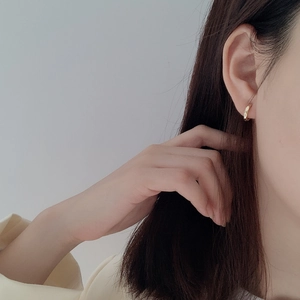 Close-up of a model wearing minimalist small gold hoop earrings in 925 sterling silver