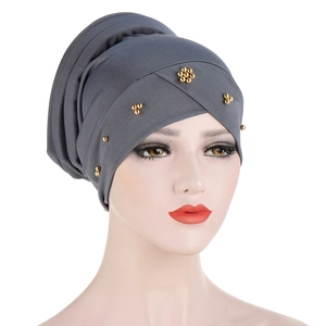 Detail of dark grey turban featuring intricate golden beadwork and pleated fabric texture