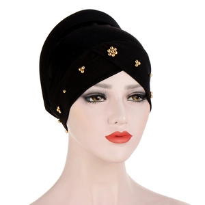 Detail of black turban hat with elegant gold bead embellishments and pleated design
