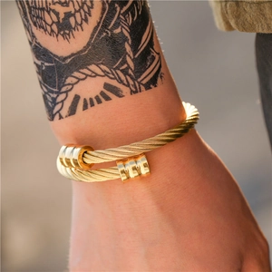 Retro goudkleurige staaldraad herenarmband met gegroefde cilinders en industrieel design