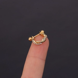 Macro shot of gold twisted helix earring with tiny clear zircons on finger