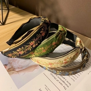 Vintage embroidered knotted headbands in four colors displayed on a rustic wooden desk