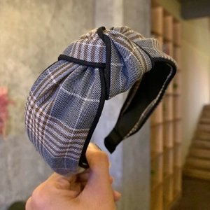 Detail of blue and grey plaid fabric headband featuring a stylish knotted design
