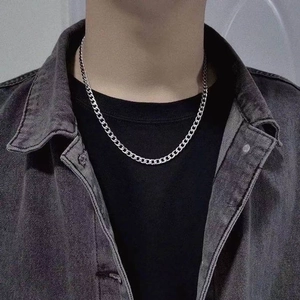 Detailed close-up of a silver titanium steel Cuban chain necklace on a male model