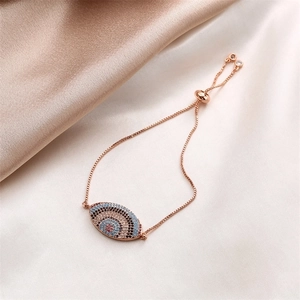 Detail of rose gold Evil Eye bracelet with colorful zircons on silk fabric background