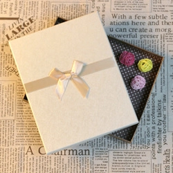 Handmade gift box with beige ribbon bow and polka dot lining on vintage newsprint