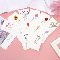 Flat lay of 10 handmade cards with real dried flowers and script text on pink background