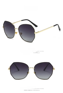 Detail view of large hexagonal metal sunglasses in black and gold with gradient lenses