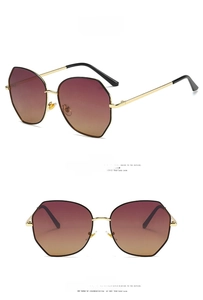 Detail of round oversized sunglasses with black gold metal frame and red-yellow gradient lens