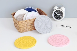 Detailed close-up of colorful round cotton woven coasters in a woven storage basket
