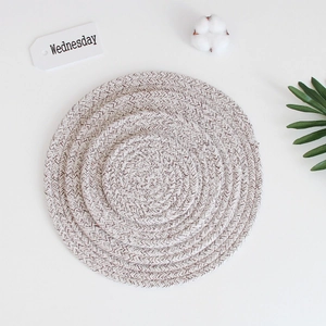 Macro detail of round woven cotton coasters in beige and brown with textured patterns