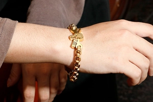 Detail of men's gold industrial bracelet with skull, wrench and hammer charms