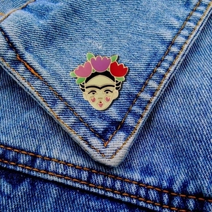 Detailed close-up of a Frida Kahlo enamel brooch on a denim jacket pocket edge
