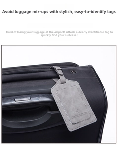 Close-up of a grey PU leather luggage tag with fine stitching and a plane logo on a black suitcase
