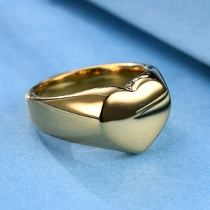 Polished golden stainless steel heart ring shown from a 45-degree angle on blue texture