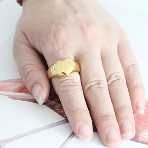Minimalist golden stainless steel heart signet ring worn on index finger for women