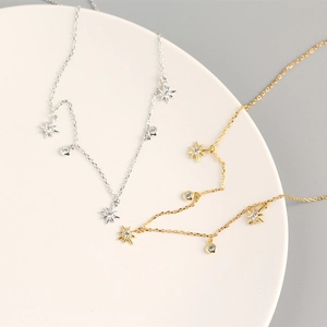 Detail of silver and gold star necklaces with sparkling crystals on a ceramic tray