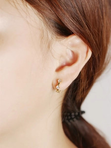Close-up of minimalist gold S925 silver hoop earrings with three inlaid zircons on ear