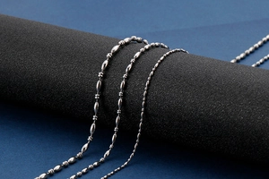 Three assorted silver stainless steel bead and bamboo chains displayed on a dark pillar