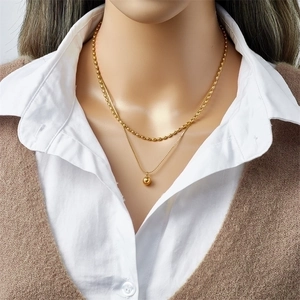 Double-layered gold titanium steel necklace with bead chain and round ball pendant on model