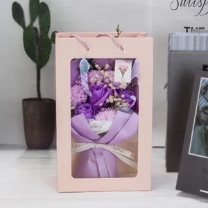 Detail showing purple soap rose and carnation bouquet in a pink windowed gift bag