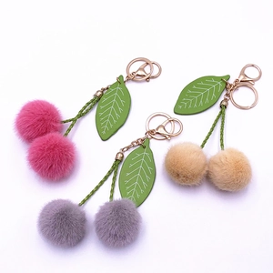 Cute plush cherry fruit keychain with soft fur balls and green leather leaves on white background