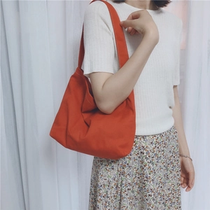 Model wearing a minimalist bright orange canvas shoulder bag for daily casual use