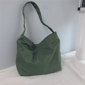 Detailed macro view of dark green canvas hobo bag with wide shoulder strap texture