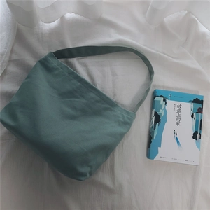 Detail view of a Morandi green canvas shoulder bag placed on soft white fabric background