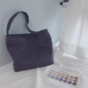 Detail of dark purple canvas shoulder bag with white topstitching and durable strap