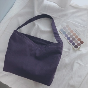 Macro shot of large purple canvas tote bag with wide shoulder straps on a soft white background