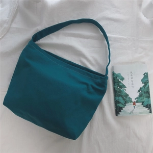 Minimalist blue-green canvas tote bag shown flat with a book on white fabric