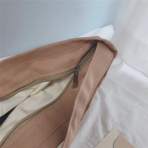 Detailed close-up of metal zipper and off-white lining on khaki canvas underarm bag