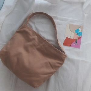 Detail of tan canvas shoulder bag with woven texture on a minimalist white backdrop
