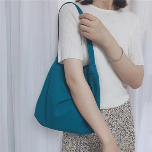 Peacock blue canvas tote bag shown worn by model to display size and minimalist aesthetic