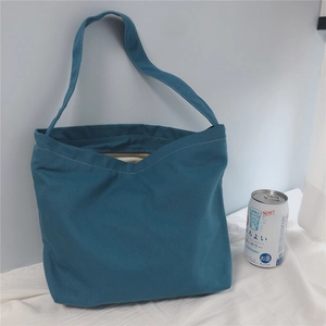 Flat lay of large turquoise canvas tote bag with shoulder strap and zipper closure
