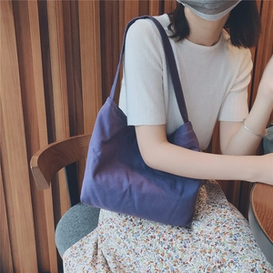 Detail view of purple canvas shoulder bag styled with white knitwear and a floral skirt