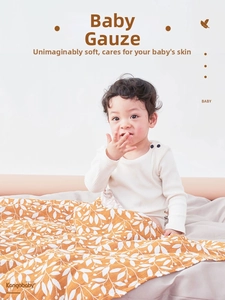 Detail of soft ginger muslin baby swaddle blanket with white leaf patterns on an infant