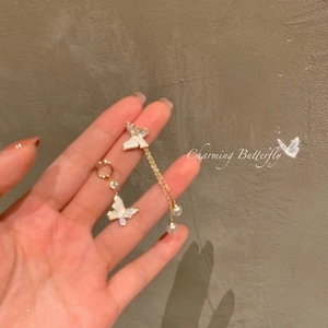 Detail of asymmetric gold butterfly earrings with pearls and shimmering sequins