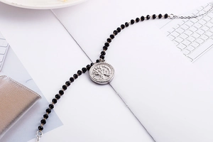 Detailed macro view of black faceted beads and silver tree of life pendant necklace