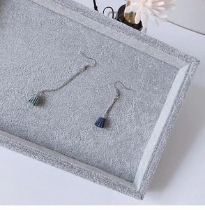 Detail of long fringe tassel earrings in blue and green on a soft velvet jewelry tray