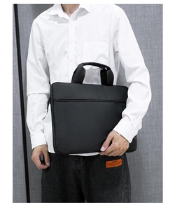Nahaufnahme der schwarzen Laptop-Tasche mit Griffen und Fronttasche, von Model gehalten
